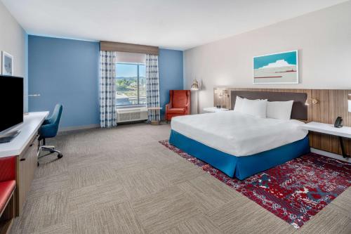 a hotel room with a bed and a desk and a tv at Hilton Garden Inn Trinidad Downtown in Trinidad