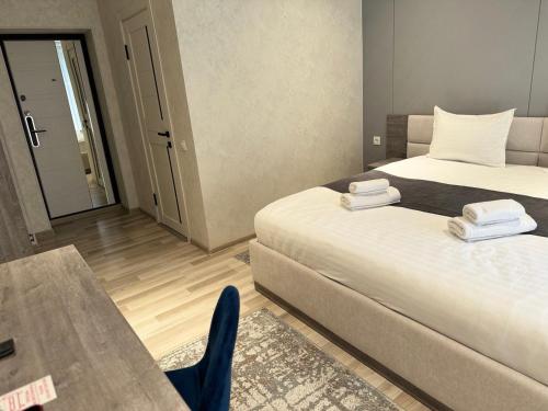a room with two beds and a table with a chair at Beshchinor Hotel in Yakkasaray