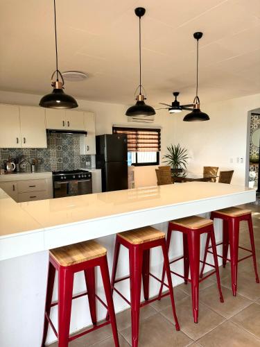 a kitchen with red stools at a large white counter at Casa Blanca Puerto Galera in Puerto Galera