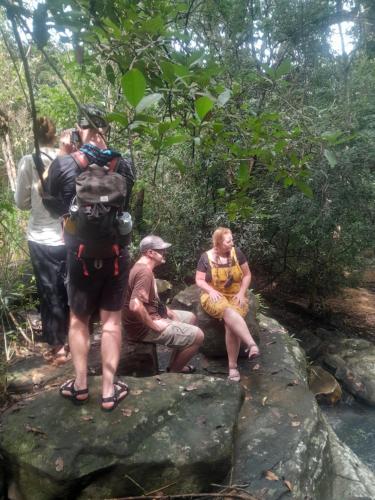 a group of people sitting on rocks next to a stream at The Happy House Nature Retreat in Talakolawela