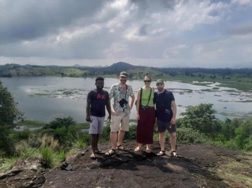 a group of people standing on a rock near a lake at The Happy House Nature Retreat in Talakolawela