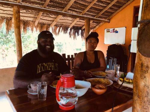 a man and a woman sitting at a table with food at The Happy House Nature Retreat in Talakolawela