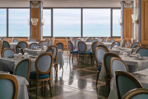 a row of tables and chairs in a room with windows at Hotel Promenade in Montesilvano