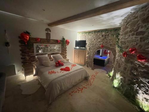 une chambre avec un lit et un mur en pierre dans l'établissement Love room chambre romantique avec Jacuzzi, à Grézieu-la-Varenne