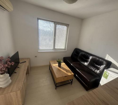 a living room with a black leather couch and a coffee table at Апартамент за гости ''ЗДРАВЕ'' in Kyustendil