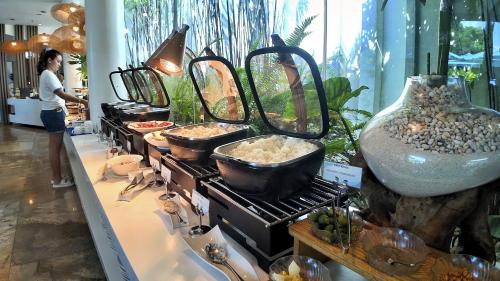 a woman standing next to a stove with pots and pans at Dominiks pink dream Studio Balcony Ocean View Balcony Fast-Wifi at Tambuli Resort High Floor in Maribago