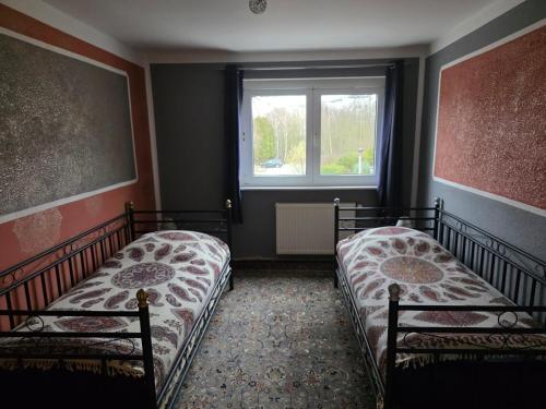 two beds in a room with a window at Shiraz-Home das Ferienhaus in Holzminden, 120qm Privatsphäre für ungestörte Erholung in Holzminden