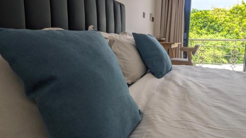 a bed with blue pillows in a room with a window at Grande Maldives Inn in Himmafushi