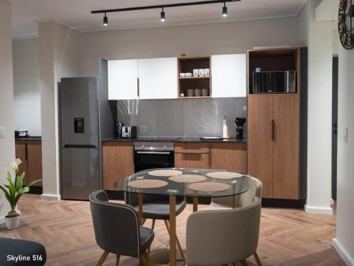 a kitchen with a glass table and chairs in a room at On Park 516 At Century City in Cape Town