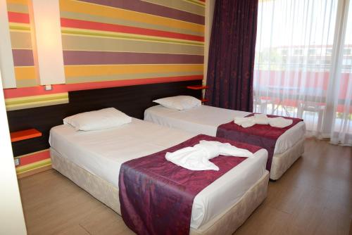 Dos camas en una habitación de hotel con paredes coloridas. en North Beach Hotel, en Primorsko