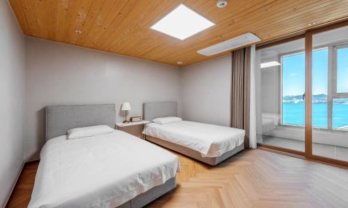 a bedroom with two beds and a large window at Busan Station BOOKING THE BAY in Busan