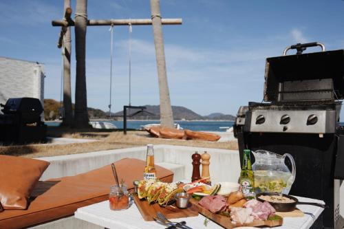 a plate of food on a table next to a grill at Alba HOTEL & Glamping in Nishinoura