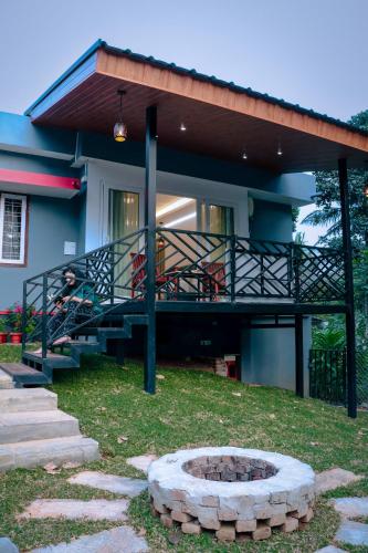 a house with a balcony and a fire pit in the yard at The Grove in Devikolam