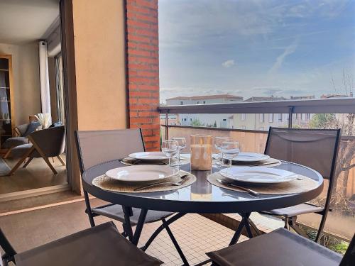 une table avec des assiettes et des verres à vin sur un balcon dans l'établissement L'Ame du Peintre - Terrasse - Parking - Centre, à Albi
