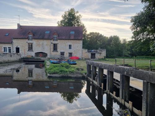 a building with a reflection in the water next to a bridge at Le Moulin de Vilaine in Châteauroux