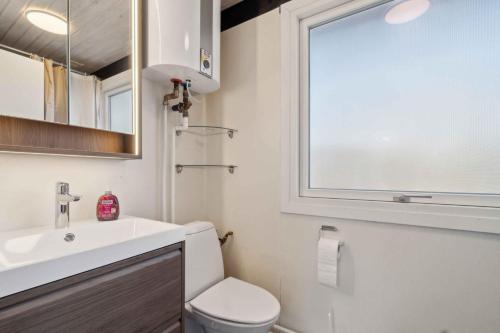 a bathroom with a toilet and a sink and a window at Cottage Near Idyllic & Peaceful Sandy Beach in Rønne