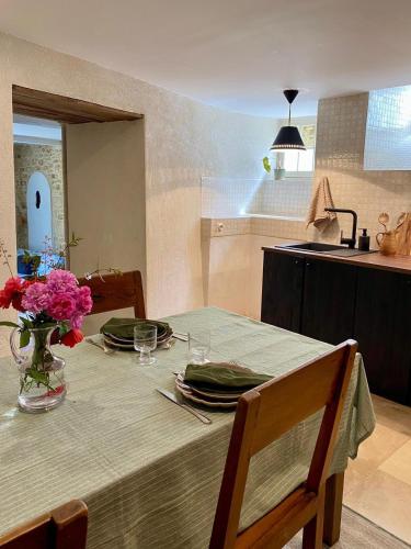 une cuisine avec une table avec un vase de fleurs dessus dans l'établissement Maison Honorine, à Saint-Geniès