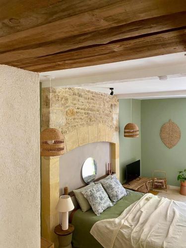 une chambre avec un lit vert et un mur en pierre dans l'établissement Maison Honorine, à Saint-Geniès