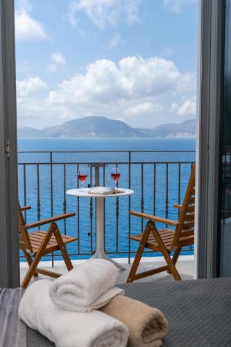 a balcony with a table and two glasses of wine at Assos Rockshore Villa by the sea in Asos