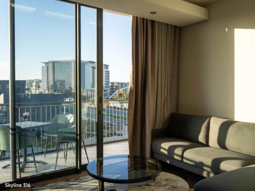 a living room with a couch and a table and a balcony at On Park 516 At Century City in Cape Town