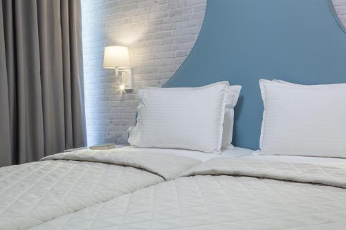 a bed with white pillows and a lamp on it at Hotel Pitsakis in Tolo