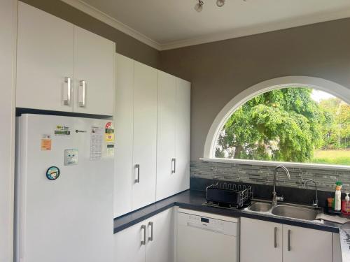 a kitchen with a sink and an arch window at Beautiful garden view 4BR house in Oamaru