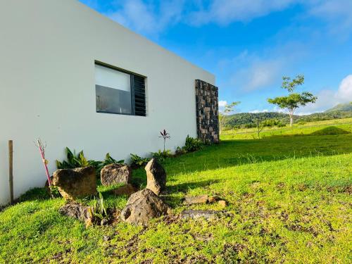 a white house on a green hill with rocks at Private Secluded Cosy Studio in Avalon Golf Estate in Bois Chéri