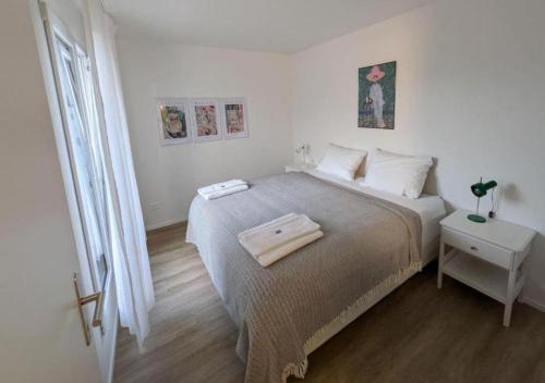 a white bedroom with a large bed and a window at UP&GREAT Apartments - Chic Urban Homes in Zürich