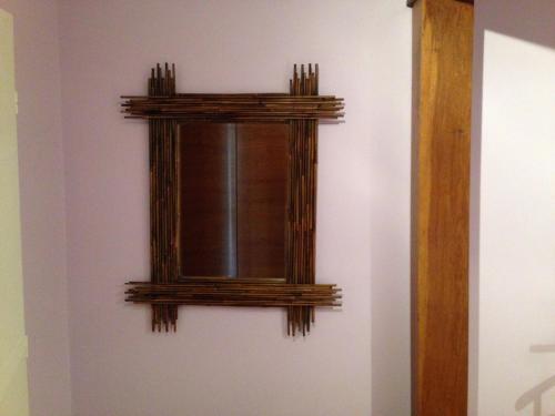 un miroir sur un mur avec un cadre en bois dans l'établissement Gîte de vacances, à Saint-Michel-de-Fronsac