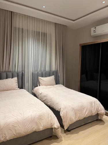 a bedroom with two beds and a window at Vera 1 Apartment شقه أنيقه بالخبر بثلاث غرف نوم وصاله تتسع ل 6 اشخاص in Al Khobar