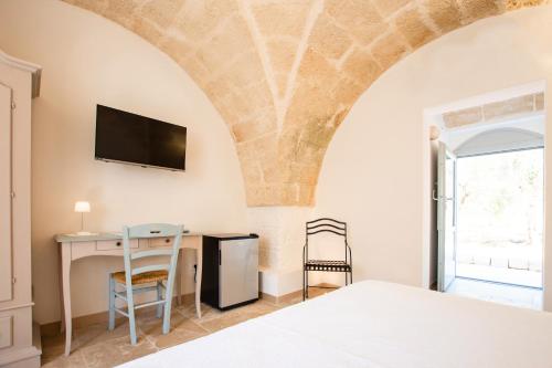a bedroom with a bed and a desk and a tv at Tenuta Mogavero in Torre Canne