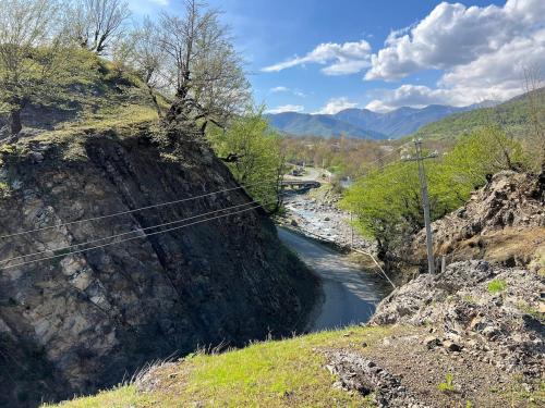 a river next to a hill with trees and mountains at Scandi House Premium in Çayqovuşan
