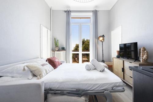 - une chambre blanche avec un grand lit et une télévision dans l'établissement Coquette studette, aperçu mer, à 400m des plages, à Villeneuve-Loubet