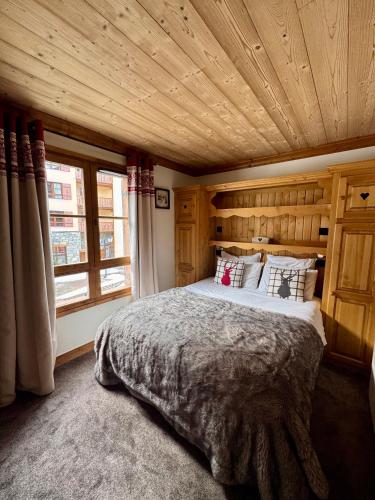 une chambre avec un grand lit avec un plafond en bois dans l'établissement ARC 1950 - Grand 3 pièces de 75 m - 8 couchages, à Bourg-Saint-Maurice