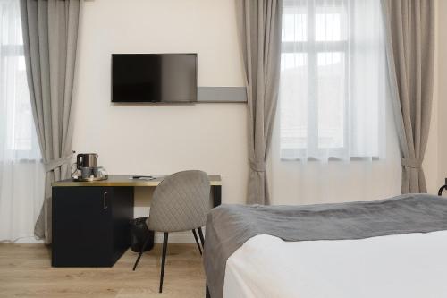 a hotel room with a bed and a desk and a tv at Hotel Atria in Braşov