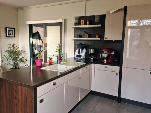 a kitchen with white cabinets and a sink at Chez Fabienne et Olivier, chambre privative avec SDB et WC, Avranches Baie du Mont Saint Michel in Avranches