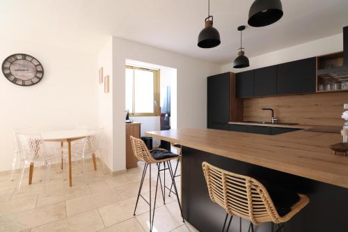 a kitchen with a counter and chairs and a clock at Sublime Appartement avec Parking Privé à Ajaccio in Ajaccio