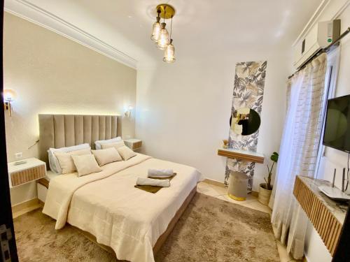 a bedroom with a large white bed and a television at Appartement B living in Agadir