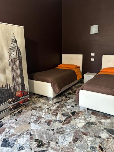 a bedroom with two beds and a painting of big ben at B&B AFFITTACAMERE Mo' MONTEIASI in Monteiasi