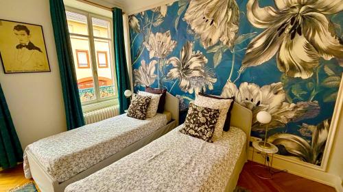 - 2 lits dans une chambre ornée d'une fresque florale dans l'établissement La Villa Alma Colmar, à Colmar