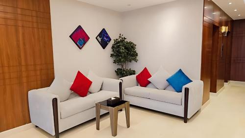 a living room with two white couches with colorful pillows at Sumou Hotel Al Khobar in Al Khobar