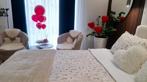a bedroom with red balloons and a bed and chairs at Josephine Apartment in Subotica