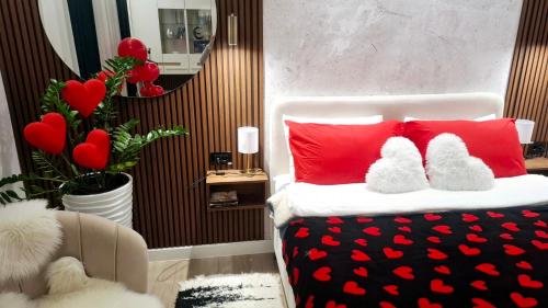 a bedroom with a bed with red pillows and a mirror at Josephine Apartment in Subotica