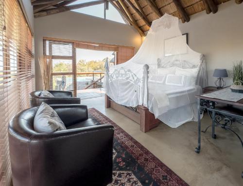 a bedroom with a bed and two chairs and a desk at Des'lgodini Lodge - PRM078 in Bela-Bela