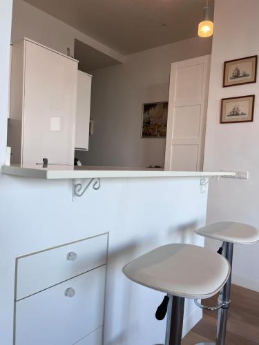 une cuisine blanche avec une table et deux tabourets dans l'établissement Appartement Trouville Palace, à Trouville-sur-Mer