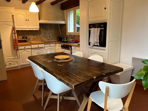 - une cuisine avec une table en bois et des chaises blanches dans l'établissement Il y a le ciel, le soleil, et la mer 4 chambres, à Bénodet