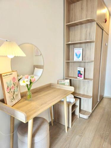 a desk with a mirror and a vase of flowers at Cloud Nine The Song Vung Tau Homestay in Vung Tau