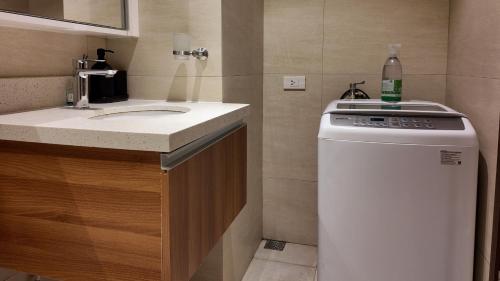 a small bathroom with a sink and a washing machine at Dominiks Comfort and silent Studio Tambuli Balcony Pool Mactan Ocean View High Floor in Lapu Lapu City