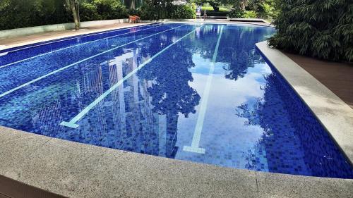 a swimming pool with a reflection of a woman in the water at Dominiks Comfort and silent Studio Tambuli Balcony Pool Mactan Ocean View High Floor in Lapu Lapu City