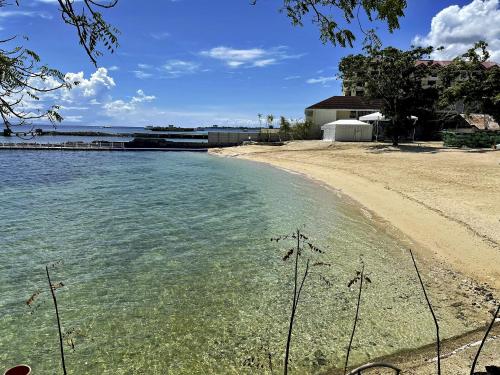 a beach with clear water next to a building at Dominiks Comfort and silent Studio Tambuli Balcony Pool Mactan Ocean View High Floor in Lapu Lapu City